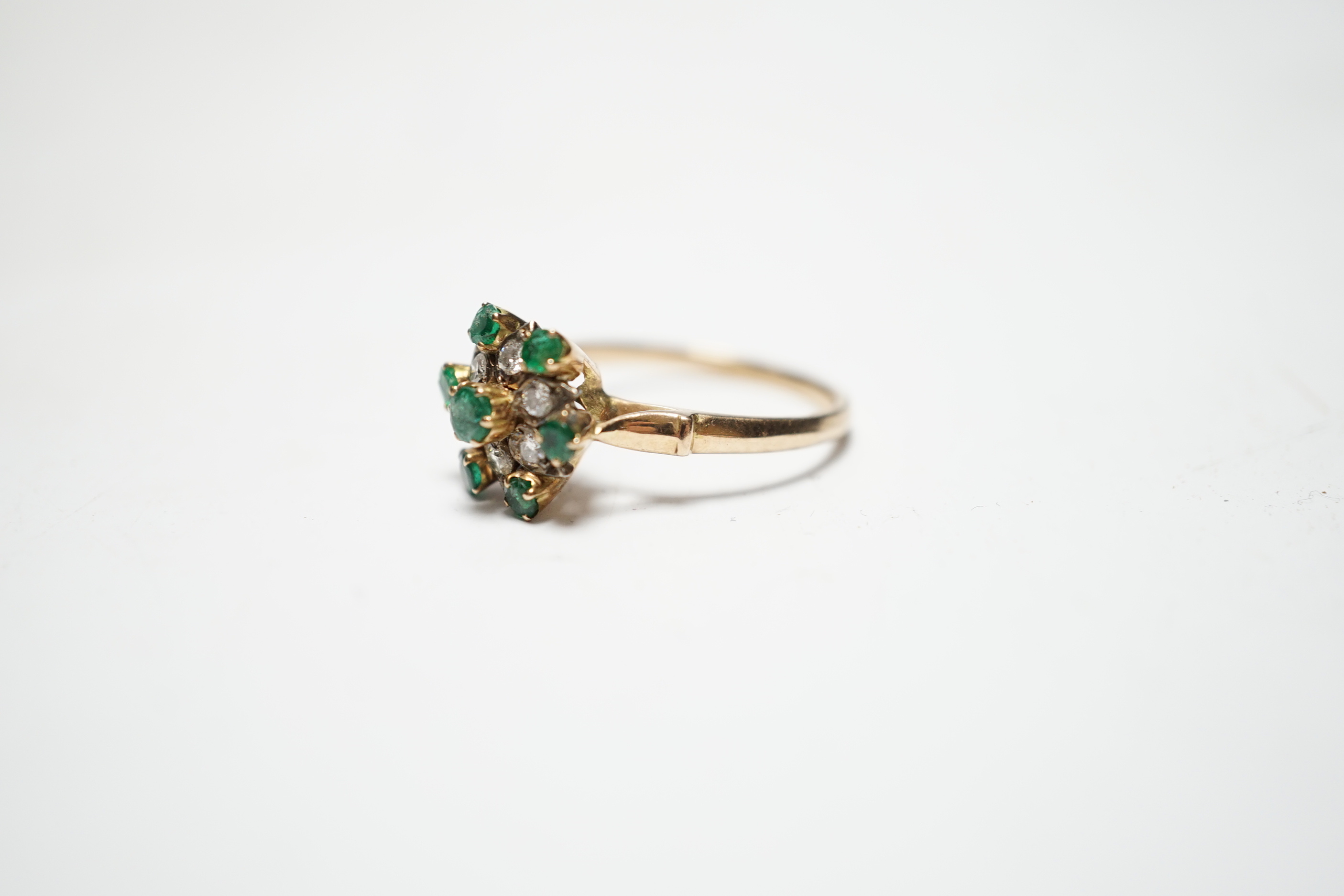 A 14ct, emerald and diamond set flowerhead cluster ring, size N/O, gross weight 3.2 grams.